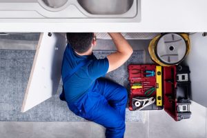 plumber working on drain pipe